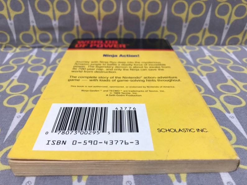 May include: Yellow and black back cover of a book titled "Worlds of Power: Ninja Action!" with a barcode and ISBN number. The book is published by Scholastic Inc.