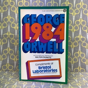 Pode incluir: Uma cópia vintage do livro "1984" de George Orwell. A capa apresenta o título em letras arrojadas e coloridas com o nome do autor. Inclui um prefácio de Walter Cronkite e uma mensagem da Bristol Laboratories.