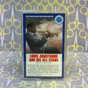 May include: A vintage cassette tape featuring Louis Armstrong and His All-Stars, titled "Satch Plays Fats." The cover art shows Armstrong playing the trumpet. The tape is labeled "Digitally Remastered Directly From The Original Analog Tapes."