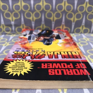 May include: A paperback novel titled "Worlds of Power TM" with a yellow starburst featuring the text "A novel based on the best-selling NINTENDO game by TECMO" and the title "NINJA GAIDEN TM" in red and black text.