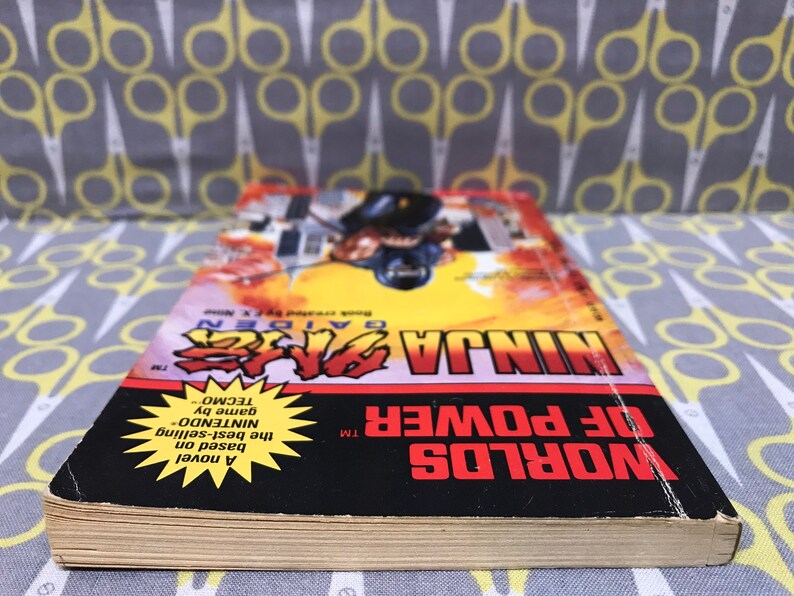 May include: A paperback novel titled "Worlds of Power TM" with a yellow starburst featuring the text "A novel based on the best-selling NINTENDO game by TECMO" and the title "NINJA GAIDEN TM" in red and black text.