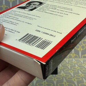 Puede incluir: Caja de cinta de cassette con el libro "Scary Stories to Tell in the Dark" de George S. Irving. La caja tiene un borde rojo e incluye el ISBN y el c&oacute;digo de barras. La cinta de cassette est&aacute; etiquetada como "CASSETTE CPN1869".