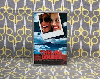 May include: A cassette tape case with a photo of two women smiling. The case is for the Thelma & Louise movie soundtrack. The text on the case reads "A Ridley Scott Film Thelma & Louise Original Motion Picture Soundtrack".