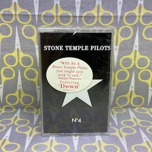 Może przedstawiać: Kaseta muzyczna Stone Temple Pilots. Obudowa kasety ma czarne tło z nazwą zespołu i tytułem albumu, "No. 4". Widoczna jest również biała gwiazda i tekst z magazynu Raygun. Prezentowany utwór to "Down".