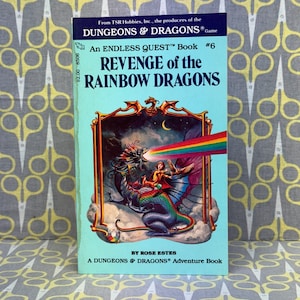 Op de afbeelding: Omslag van een Dungeons & Dragons-avontuurboek getiteld "Revenge of the Rainbow Dragons." De omslag toont een regenboogdraak met een ruiter en een halve maan op de achtergrond.