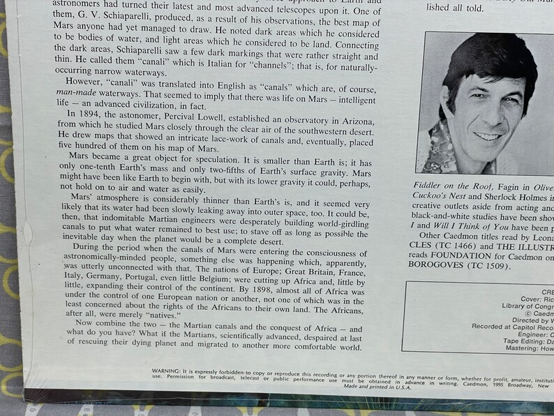 May include: A black and white photo of a man with short, dark hair and a smile. The man is wearing a light-colored shirt. The text "Fiddler on the Roof, Fagin in Oliver! Cuckoo's Nest and Sherlock Holmes in creative outlets aside from acting and black-and-white studies have been shown. I and Will I Think of You have been produced. Other Caedmon titles read by Leon..." is visible in the image.