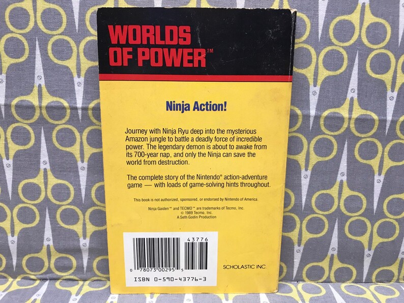 May include: Yellow and black book cover for the Worlds of Power game, featuring a ninja character and the title "Ninja Action!" The back cover includes a description of the game, copyright information, and a barcode.