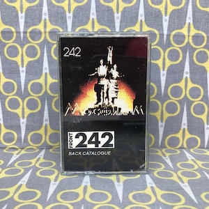May include: A black cassette tape with the number "242" printed on the front and back. The front of the tape features a black and white image of a statue with the word "Moscow" printed below it. The back of the tape has the text "FRONT 242 BACK CATALOGUE".