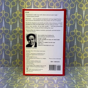 Puede incluir: Una funda de casete de audio vintage para "More Scary Stories to Tell in the Dark". La funda roja y blanca presenta texto y un retrato de George S. Irving. La parte posterior de la funda incluye una rese&ntilde;a y un ISBN.