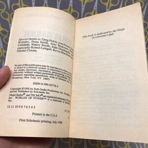 May include: A book with a white cover and black text. The title is "Ninja Gaiden" and the text on the back cover includes the ISBN number 0-590-43776-3 and the copyright information. The book is dedicated to the Ninja in everyone's dad.