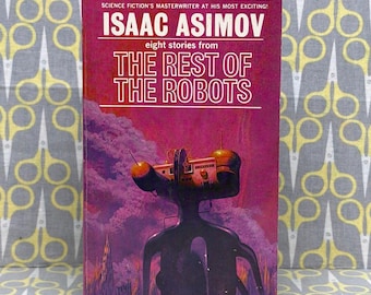 Może przedstawiać: Książka w miękkiej oprawie w stylu vintage zatytułowana The Rest of the Robots autorstwa Isaaca Asimova. Okładka ma magentowe i fioletowe tło z ciemną, abstrakcyjną postacią robota i futurystyczną strukturą. Tekst zawiera Pyramid, T-2565 i 75c.