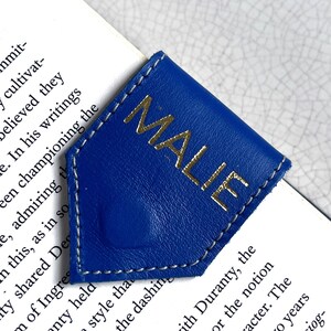 May include: A blue leather bookmark with a gold inscription that reads "MALIE".