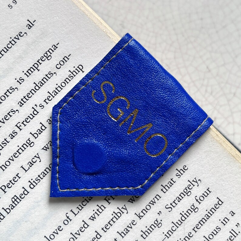 May include: A blue leather bookmark with gold lettering that reads "SGMO".