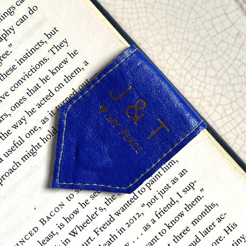 May include: A blue leather bookmark with gold lettering that reads "J & T My Place".