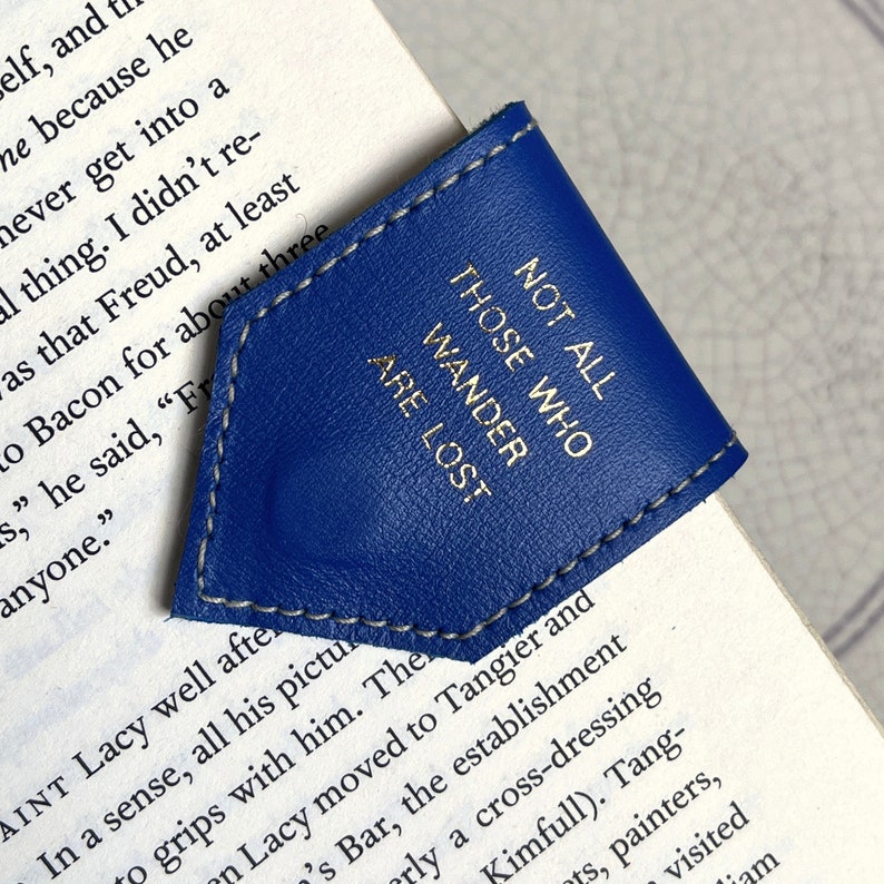May include: A blue leather bookmark with a gold inscription that reads "Not all those who wander are lost."