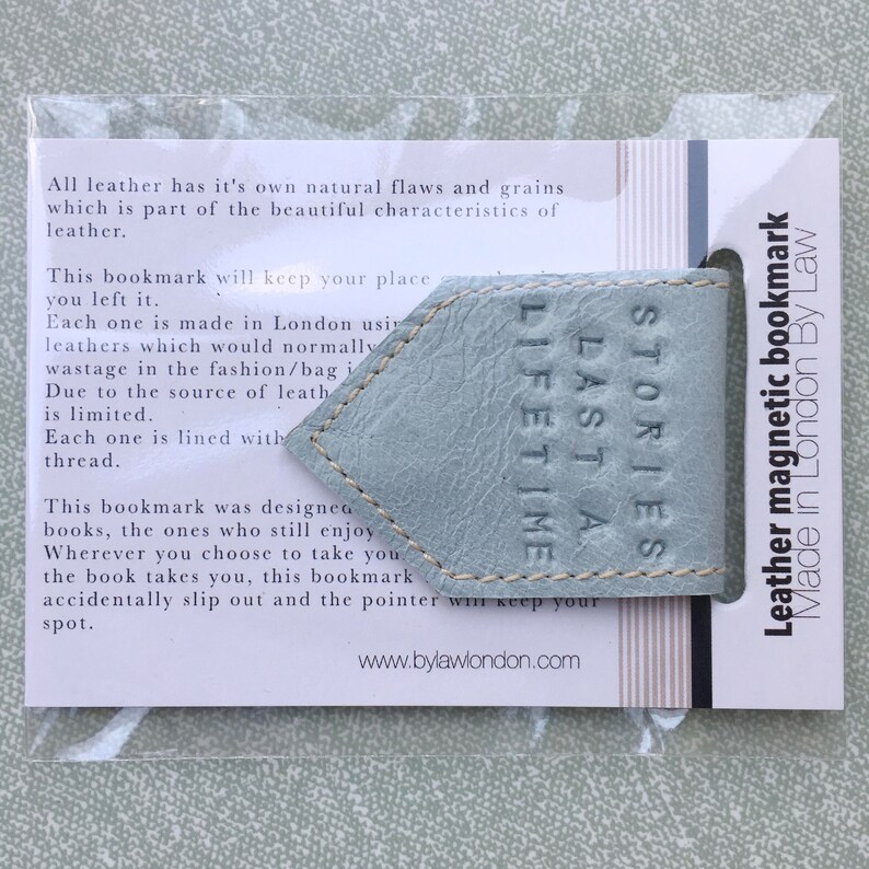 May include: A light blue leather bookmark with the text "Stories Last A Lifetime" embossed on it. The bookmark is magnetic and made in London by Law.