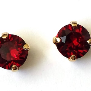 May include: A pair of gold stud earrings with red round gemstones.