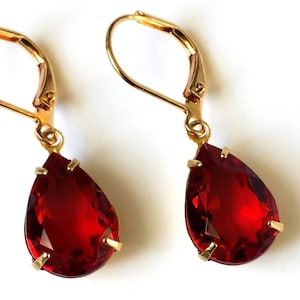May include: A pair of gold dangle earrings with teardrop-shaped red gemstones.