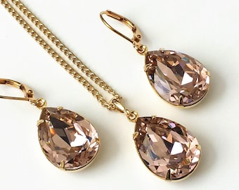 May include: A gold necklace and earrings set with teardrop-shaped blush pink crystals.