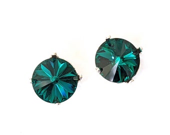 May include: A pair of emerald green crystal earrings with silver settings. The crystals are round and have a faceted design.