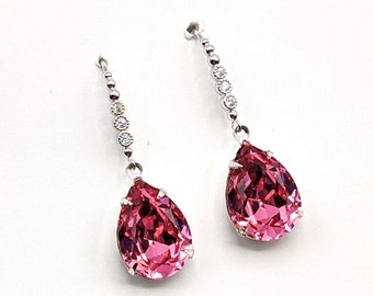 May include: A pair of dangle earrings with a pink teardrop-shaped crystal and a silver chain with clear crystals.
