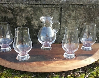 Puede incluir: Cinco vasos de whisky de vidrio transparente y una jarra de vidrio transparente en una bandeja de servicio de madera. Los vasos son todos del mismo tamaño y forma, y la jarra tiene un asa.