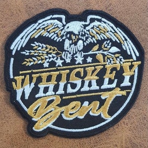 May include: Black and gold embroidered patch with an eagle design and the text "Whiskey Bent".