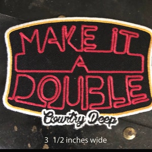 May include: Red and white embroidered patch with the text "Make it a Double" and the words "Country Deep" in a white cursive font. The patch is 2 1/2 inches tall and 3 1/2 inches wide.