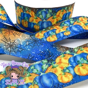 Puede incluir: Un rollo de cinta con temática de calabaza azul y naranja con un diseño de telaraña. La cinta presenta un patrón repetido de calabazas azules y naranjas. El texto "Tie a Bow On Supplies" es visible.