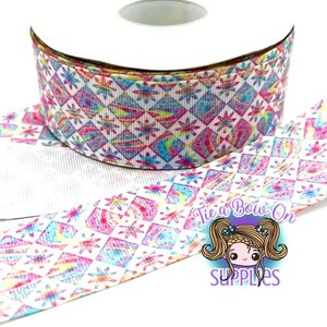 Puede incluir: Un rollo de cinta decorativa con un patrón geométrico repetido en tonos de rosa, azul, amarillo y verde. La cinta presenta un diseño de diamantes y flores. El logotipo "Tie a Bow On SUPPLIES" es visible en la cinta.