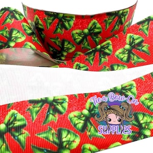 Puede incluir: Una cinta de grosgrain roja con un patrón repetitivo de lazos verdes con pequeños toques amarillos. La cinta tiene una superficie texturizada y acanalada, e incluye un logotipo de marca de agua con un personaje y el texto Tie a Bow On Supplies.