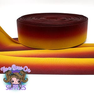 May include: A roll of ombre ribbon in shades of burgundy, orange, and yellow. The ribbon is ribbed and has a gradient effect, transitioning from dark to light. The logo "Tie a Bow On SUPPLIES" is visible in the lower left corner.