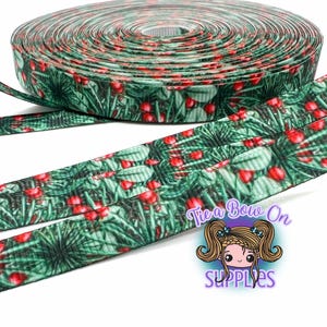 May include: A roll of green ribbon featuring a pattern of red berries and green leaves. The ribbon is unrolled, displaying the design. The image includes the text "Tie a Bow On SUPPLIES". The ribbon is suitable for crafts.