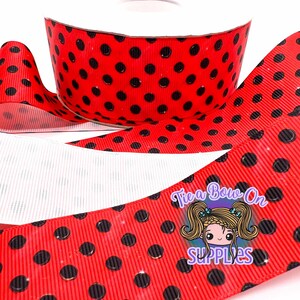 May include: Red ribbon with black polka dots, unrolled from a spool. The ribbon has a glossy finish and is suitable for crafting and gift wrapping. The image includes a logo that says "Tie a Bow On SUPPLIES".