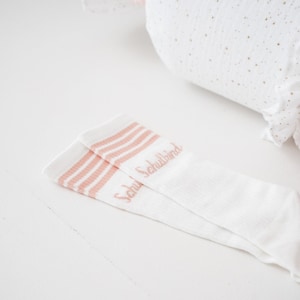 Könnte beinhalten: Weiße Socken mit rosa Streifen und dem Text "Schuhbund" in rosa.