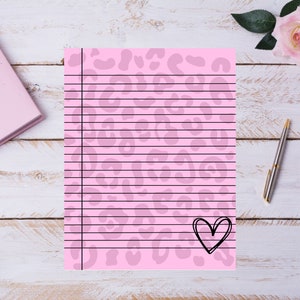 Könnte beinhalten: Rosa liniertes Papier mit Leopardenmuster und einer schwarzen Herz-Kritzelei. Das Papier hat eine vertikale schwarze Linie und horizontale schwarze Linien zum Schreiben. Ein rosa Notizbuch, ein Stift und Rosen befinden sich im Hintergrund.