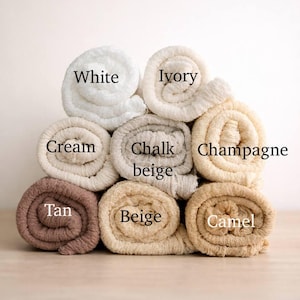 A stack of rolled towels in various colors, including white, cream, chalk, champagne, tan, beige, and camel.