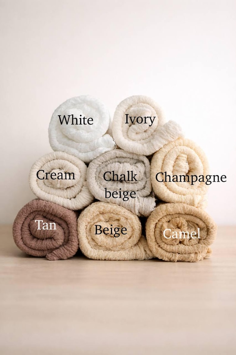 A stack of rolled towels in various colors, including white, cream, chalk, champagne, tan, beige, and camel.