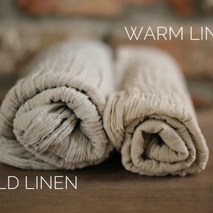 Two rolled-up beige towels, one labeled "Warm Linen" and the other "Cold Linen", placed on a wooden surface.