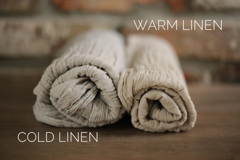 Two rolled-up beige towels, one labeled "Warm Linen" and the other "Cold Linen", placed on a wooden surface.