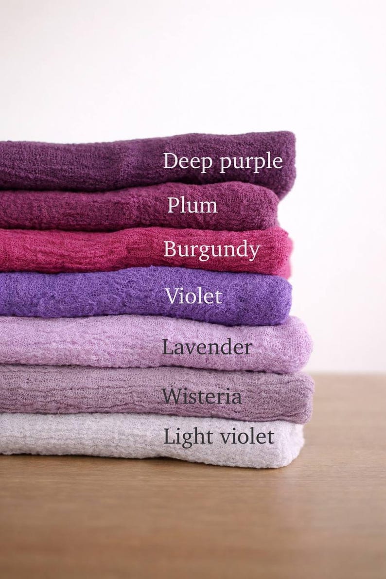 A stack of six towels in various shades of purple, including deep purple, plum, burgundy, violet, lavender, and light violet.