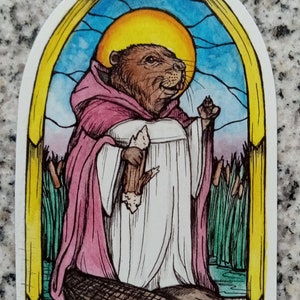 May include: A watercolor illustration of a beaver wearing a robe and holding a stick. The beaver is depicted in a stained glass window setting with a halo above its head. The background features a blue sky, green reeds, and a body of water.