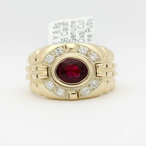 May include: A gold ring with a large oval ruby surrounded by smaller diamonds. The ring has a textured band.