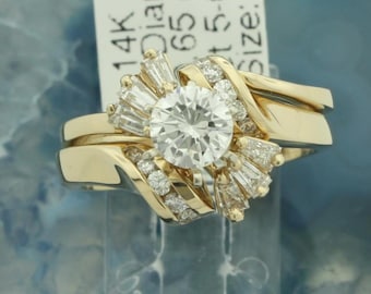 May include: A 14k gold engagement ring set with a large round center stone and a halo of smaller baguette and round diamonds. The band is a twisted design with a matching wedding band.