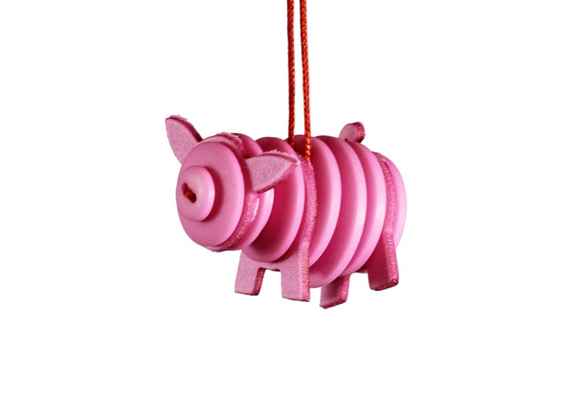 May include: A pink pig ornament made of stacked circles, hanging from a red string.