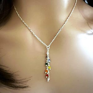 May include: A silver chain necklace with a dangling charm featuring a cascade of colorful beads in a rainbow pattern.
