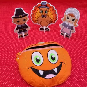 May include: A set of three felt Thanksgiving characters, including a pilgrim, a turkey, and a pilgrim girl, with a smiling orange pumpkin-shaped bag.