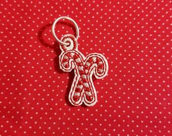 May include: A silver charm with a red and white candy cane design. The charm is attached to a silver ring.