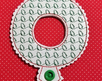 May include: White leather ornament with a green embroidered design of pine trees. The ornament has a scalloped edge and a green button.