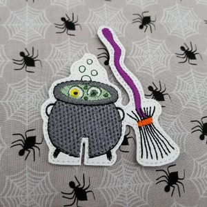 Può includere: Toppa ricamata da stirare con un calderone con liquido verde bollente e due occhi gialli, e una scopa viola e arancione.